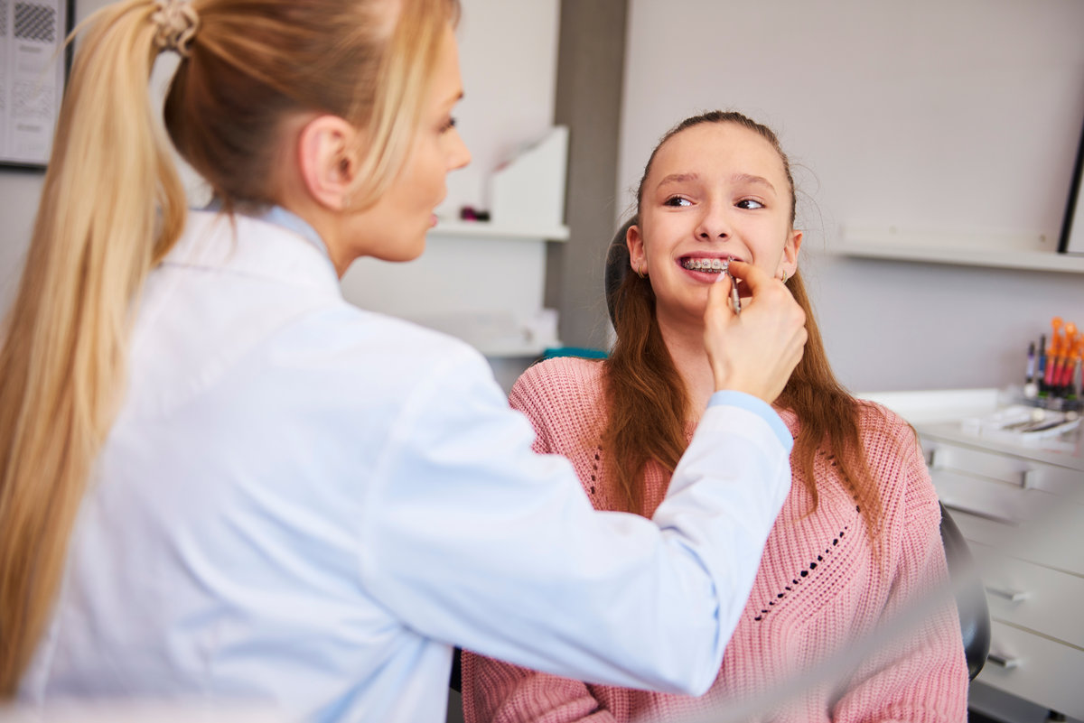 Young orthodontist checking patient in dentist's office
